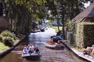 Home Elektrische punter vaart langs pittoresk Giethoorn dorp met karakteristieke bruggetjes en waterwegen in nationaal park